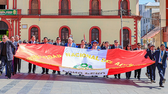 En el marco del 169 aniversario institucional, que será el próximo 29 de agosto, la Universidad Nacional del Altiplano de Puno, participó en la ceremonia de izamiento del Pabellón Nacional y en el desfile cívico militar desarrollado en la Plaza Mayor de la ciudad. El acto fue encabezado por el Rector, Dr. Paulino Machaca Ari, quien, acompañado de los Vicerrectores, Dr. Mario Cuentas Alvarado y Dr. Ariel Velazco Cárdenas, el director de la Escuela de Posgrado, Dr. Walter Tudela Mamani, decanos de facultades,